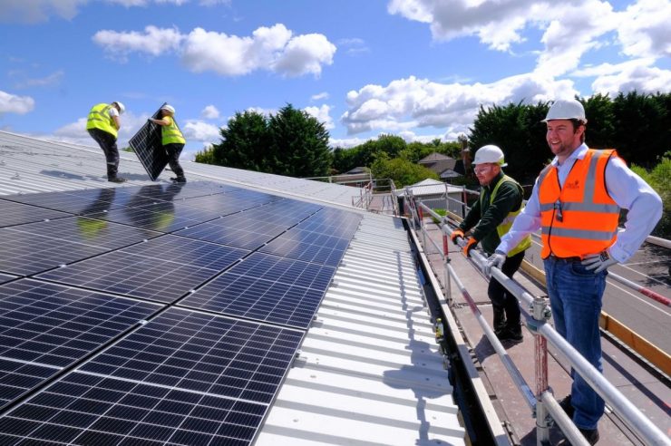 Picture of people installing solar panels to a roof.